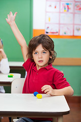 Image showing Boy With Hand Raised Sitting At Desk