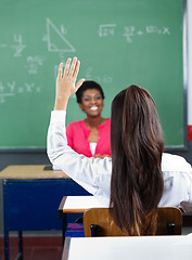 Image showing Rear View Of Schoolgirl Raising Hand In Classroom