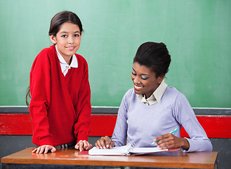 Image showing Portrait Of Schoolgirl With Teacher Reading Binder At Desk