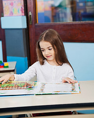 Image showing Girl Opening Popup Book At Desk In