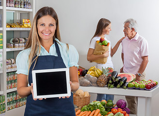 Image showing Saleswoman Displaying Tablet With Customers In Background