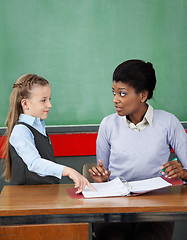 Image showing Schoolgirl Pointing In Binder While Teacher Looking At Her