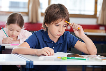 Image showing Thoughtful Schoolboy Sitting At Desk