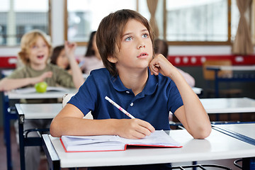 Image showing Boy Looking Up While Writing At Desk