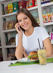 Image showing Woman Using Phone While Having Snacks In Store
