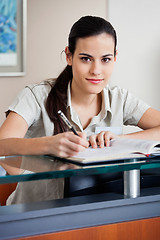 Image showing Female Receptionist Writing In Book