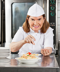 Image showing Mature Female Chef Garnishing Dish