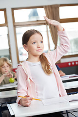 Image showing Schoolgirl Looking Away While Raising Hand In Classroom