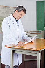 Image showing Male Teacher Reading Paper At Desk