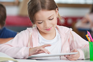 Image showing Schoolgirl Smiling While Using Tablet At Desk