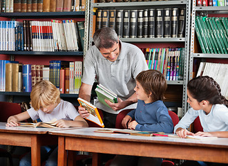 Image showing Mature Teacher Showing Book To Schoolboy In Library