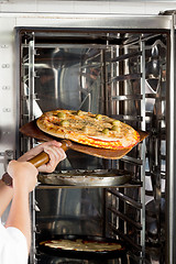 Image showing Chef's Hands Placing Pizza In Oven