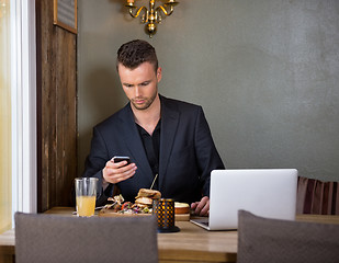 Image showing Businessman Messaging On Mobilephone While Having Meal In Cafe