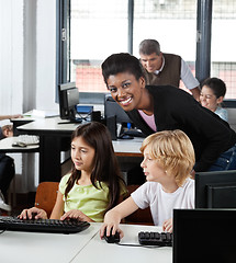 Image showing Female Teacher With Students At Desk