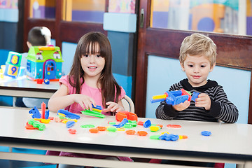 Image showing Cute Girl With Friend Playing Blocks At Desk In Classroom