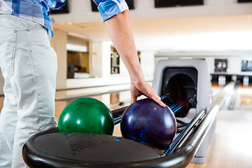 Image showing Man's Hand Picking Up Bowling Ball From Rack