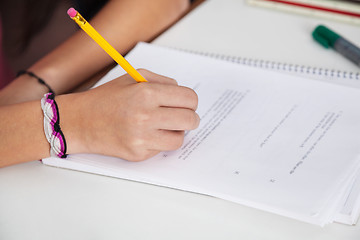 Image showing Schoolgirl Writing On Paper At Desk