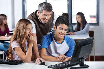 Image showing Happy Mature Teacher And Students Using Computer