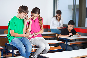 Image showing Teenage Schoolchildren Listening Music In Classroom