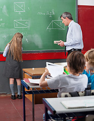 Image showing Rear View Of Little Schoolgirl Writing On Board