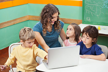 Image showing Children Using Laptop While Teacher Assisting Them