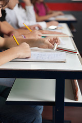 Image showing Schoolchildren Writing In A Row At Desk In Classroom