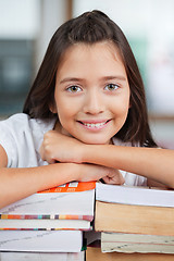 Image showing Schoolgirl Leaning On Stack Of Books In Classroom