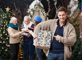 Image showing Man Pointing At Christmas Present With Family In Background