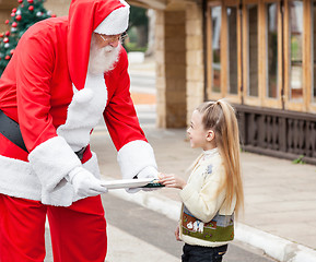 Image showing Santa Claus Offering Cookies To Girl