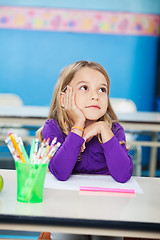 Image showing Girl With Hand On Chin Sitting At Desk In Kindergarten