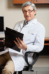 Image showing Mature Doctor Holding Clipboard