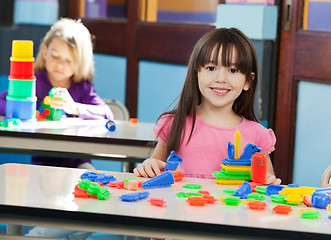 Image showing Girl With Construction Block While Friend Playing In Background