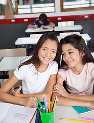 Image showing Schoolgirl Sitting With Classmate At Desk In Classroom