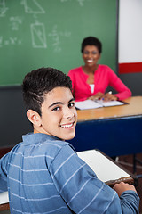 Image showing Happy Teenage Schoolboy Sitting At Desk