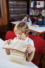 Image showing Schoolboy With Stacked Books Reading In Library