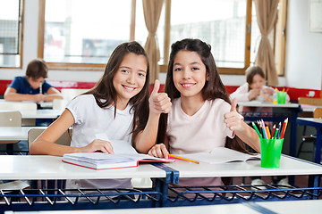 Image showing Happy Schoolgirls Gesturing Thumbs Up At Desk