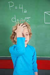 Image showing Sad Schoolboy Standing By Board In Classroom