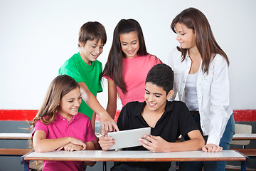 Image showing Schoolboy Pointing At Tablet With Classmates In Classroom