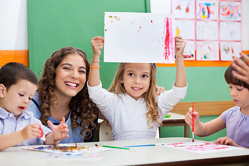 Image showing Teacher With Girl Showing Drawing At Desk