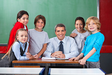 Image showing Confident Male Teacher With Schoolchildren  At Desk