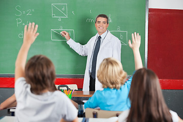 Image showing Teacher Teaching While Students Raising Hands