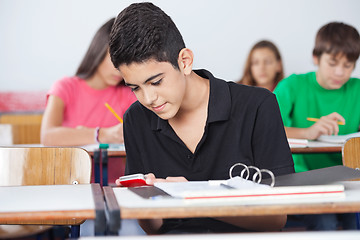 Image showing Teenage Schoolboy Text Messaging At Desk