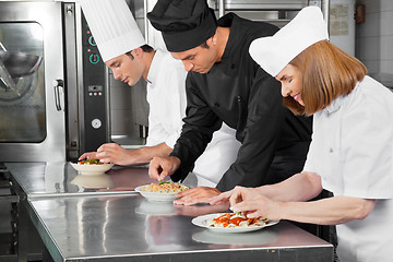 Image showing Chefs Garnishing Dishes On Counter