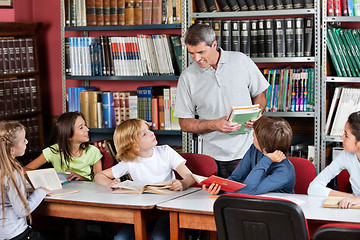 Image showing Teacher Communicating With Students Sitting At Table In Library