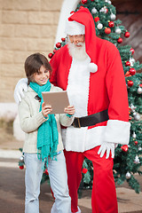Image showing Boy Showing Digital Tablet To Santa Claus
