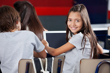 Image showing Schoolgirl Holding Digital Tablet At Desk In Classroom