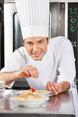 Image showing Happy Male Chef Sprinkling Spices On Dish