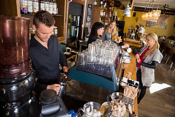 Image showing Bartender Working At Counter While Female Colleague Serving Coff