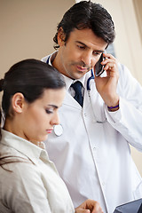 Image showing Doctor Attending Call While Standing With Colleague