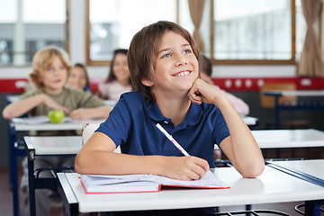 Image showing Schoolboy Looking Up While Studying At Desk